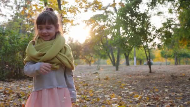 Menina pegando bolhas de sabão na luz solar, criança feliz rindo e brincando — Vídeo de Stock