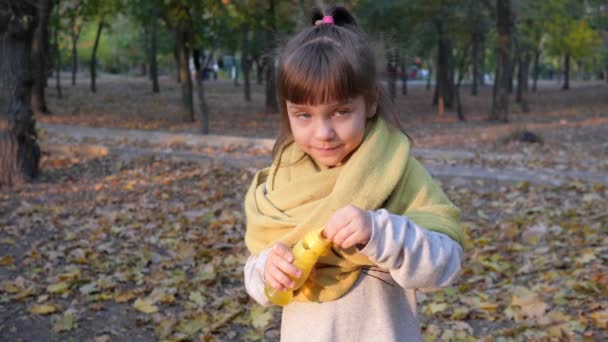 Szczęśliwy dziecko w szalik dmuchanie bańki mydlane zabawy w kamery na zewnątrz w parku — Wideo stockowe