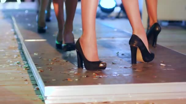 Beautiful legs of models in black footwear go along catwalk on fashion show — Stock Video