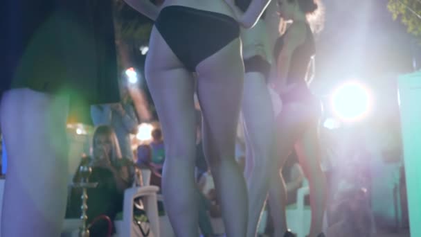Belas mulheres idiotas close-up em iluminação de holofotes, mulheres de pernas longas ir um após o outro contra os espectadores — Vídeo de Stock