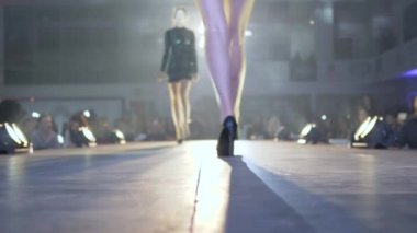Moda fuarında kadın ayakları manken podyumunda yavaş çekimde yürüyor.