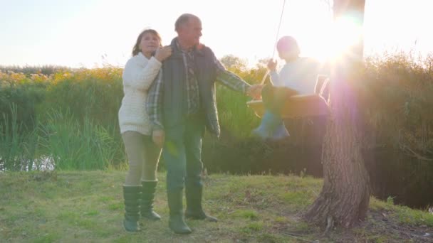 Amando o par sênior com o neto que descansa no lago que bulrush coberto no outono em férias — Vídeo de Stock