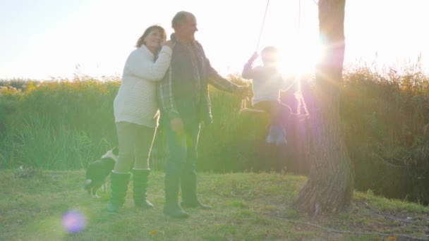 스윙을 하는 귀여운 소년 과 행복 한 노부부는 휴일에 밖에서 즐거운 시간을 보낸다 — 비디오