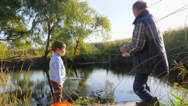 Nyári horgászat a tavon, nagypapa unokákkal jól érzik magukat a természetben meleg időben — Stock videók