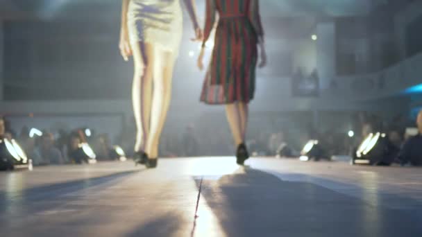 ヒールの高い靴の美しい女性の足は、ファッションのディフェイルショーのライトランプでキャットウォークに沿って行く — ストック動画