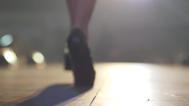 Preto sapatos de salto alto close-up no pés fêmea ir ao longo pódio no fundo borrado — Vídeo de Stock