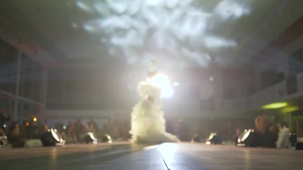 Designer clothes with feathers on models walking along catwalk in front of audience of people — Stock Video