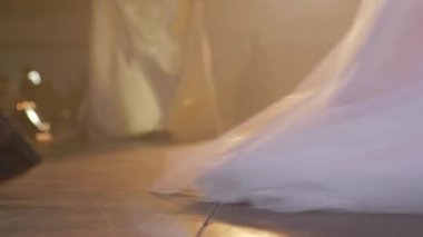 Modellerin bacaklarında yakın plan ayakkabılar, moda şovunda farklı renklerde uzun elbiseler.