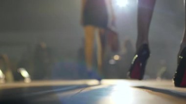 Moda defilesi, rahat topuklu ayakkabılar giyen ince manken bacakları podyumda dumana karışıyor.