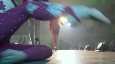 Modern moda şovu, jimnastikçiler ve mankenler şık yüksek topuklu takımlarla podyumda projektörlerle aydınlatılıyor.