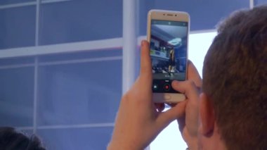 Moda şovunda cep telefonuyla podyumda yeni kıyafet koleksiyonu yapan modellerle video çekiyor.