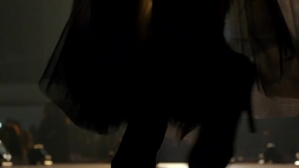 Models in Designerklamotten laufen während der Modenschau im Scheinwerferlicht über den Laufsteg, Hintergrund unscharf — Stockvideo
