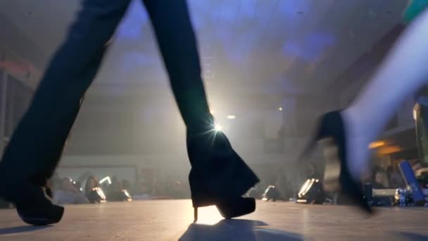 Fashionable entertainment, womens legs on high-heeled go through stage in bright spotlights — Stock Video