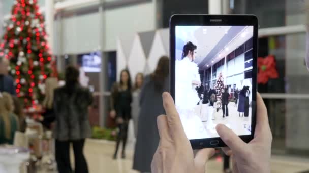 Homem dispara vídeo em tablet close-up em Ano Novo festa corporativa perto da árvore de Natal no quarto — Vídeo de Stock