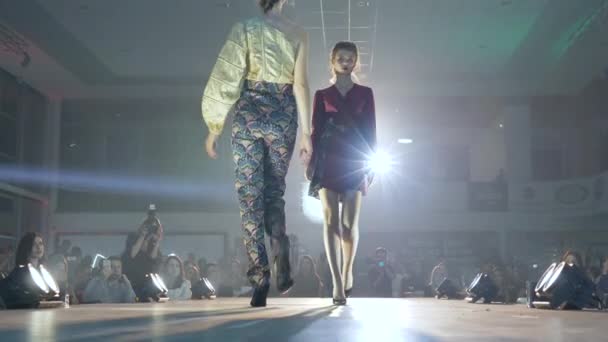 Desfile de moda, modelos profissionais apresentam nova coleção de trajes femininos no pódio iluminado por holofotes — Vídeo de Stock