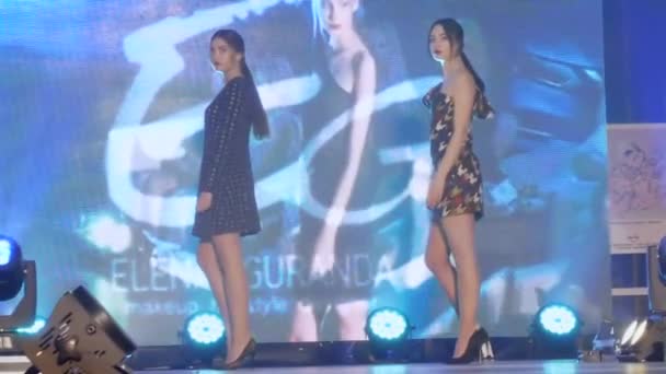 Fashion business, jonge modellen in stijlvolle jurken poseren in de schijnwerpers op catwalk op de achtergrond van groot scherm — Stockvideo