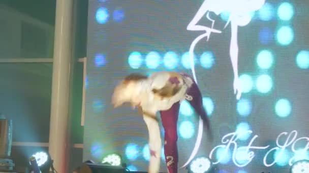 Fiatal tornász egy gyönyörű öltönyben akrobatikus gyakorlatokat végez a pódiumon közelről — Stock videók