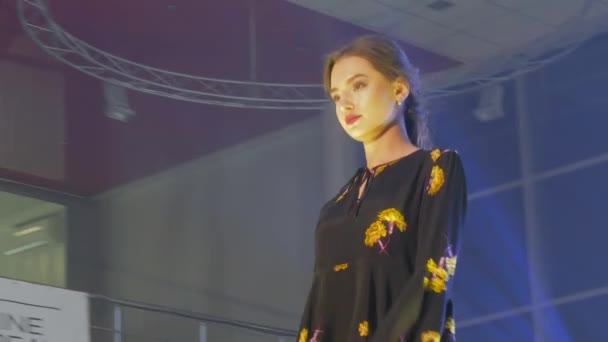 Jong model in stijlvolle jurk poseert in de schijnwerpers op catwalk close-up, fashion business — Stockvideo