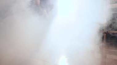 İnce ayaklı ayakkabı mankeni ağır çekimde kalın sisten çıkar.