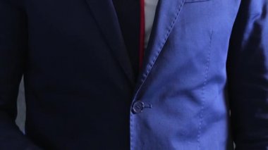 Smokinli şık bir iş adamı parmağında nişan yüzüğüyle gri beton duvara karşı kol saati takıyor.