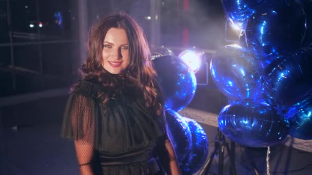 Dárek k oslavě, krásná brunetka držící dárkovou krabičku s bílou mašlí v blízkosti modrých balónků v jasném osvětlení — Stock video