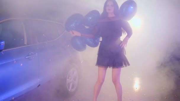Vida rica, fêmea elegante com balões azuis na mão dançando no estacionamento perto do carro no nevoeiro — Vídeo de Stock