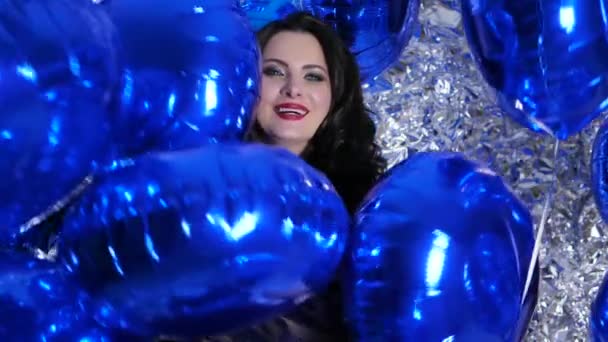 Attractive brunette with colored balloons on background shiny wall — Wideo stockowe