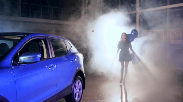 Chic chica con inflable globos stands cerca de coche en humo entre vuelo confeti — Vídeo de stock