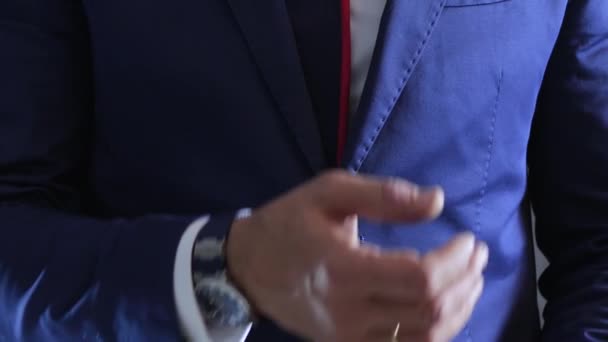 Hodiny na rukou ženatého muže v obleku s kravatou a bílou košilí proti šedé zdi — Stock video