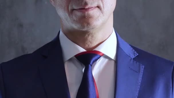 Bräutigam im Smoking trägt Krawatte am Kragen auf Hintergrund einer grauen Betonwand — Stockvideo
