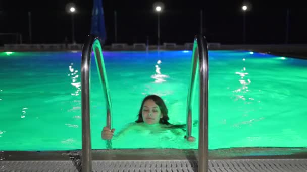 Forma femenina nadar en la noche Piscina con iluminación de color — Vídeos de Stock