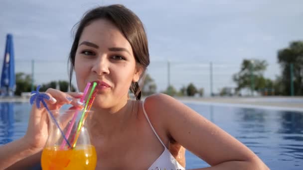 Portré gyönyörű lány, amely ivás színes koktél medence szabadtéri nyári vakáció — Stock videók