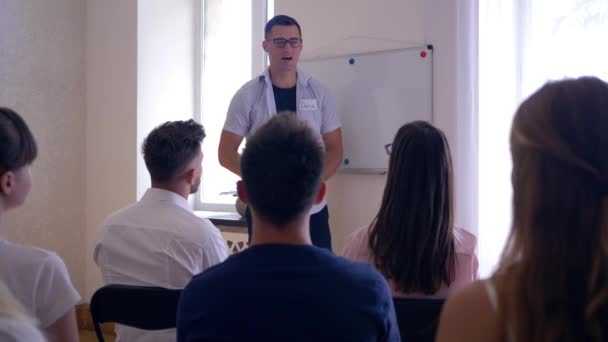 Trenér školení, vedoucí týmu představuje nový obchodní plán na tabuli pro aktivní kolegy v místnosti — Stock video