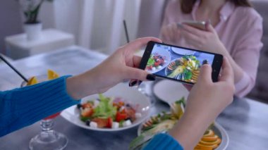 Yemek fotoğrafı, sosyal medya için sağlıklı kahvaltı sırasında vejetaryen yemeği fotoğrafları için cep telefonu kullanan bir kız kolu.