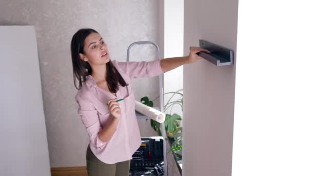 New owner of apartment does repairs and hangs shelf on wall indoors — Stock Video