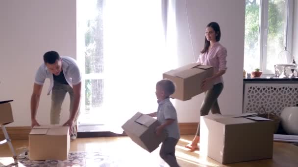 stěhování do nového bytu, šťastná rodina s malým chlapečkem těší nový domov po opravě mezi krabicemi s věcmi