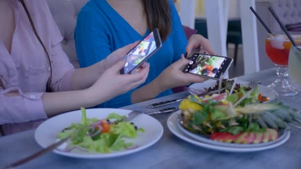 Foto de alimentos en el teléfono inteligente, bloggers niñas toman fotos de la hermosa comida útil en el teléfono celular durante el almuerzo durante la dieta para la pérdida de peso en la cafetería — Vídeos de Stock