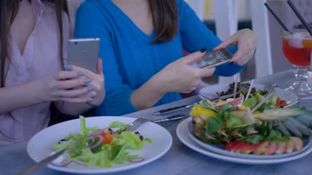 Handen van vrouwen vrienden met behulp van mobiele telefoon voor foto van mooie salade tijdens een gezond diner tijdens dieet voor gewichtsverlies in restaurant — Stockvideo