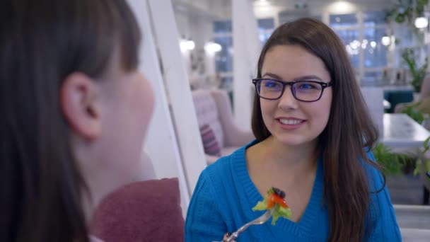 Ξεκουραστείτε στο καφέ, χαρούμενα κορίτσια με γυαλιά επικοινωνούν κατά τη διάρκεια του brunch στο εστιατόριο — Αρχείο Βίντεο