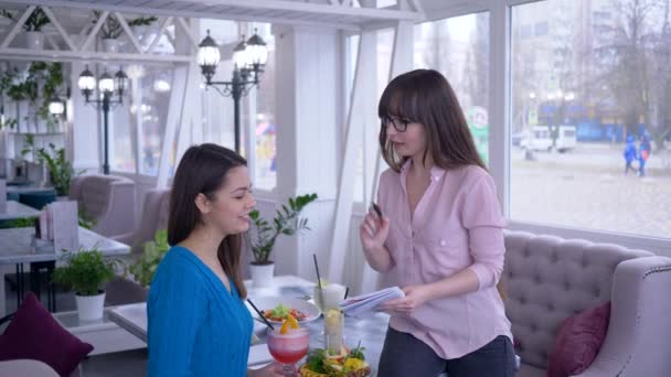 Gesunde Ernährung, junge Frauen während des Mittagessens mit dem Ziel, Gewicht zu verlieren, schreiben im Café sitzend Speiseplan auf — Stockvideo