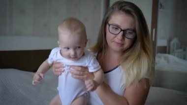Stres, gözlüklü gergin anne sık sık elinde bebekle yatakta oturuyor.