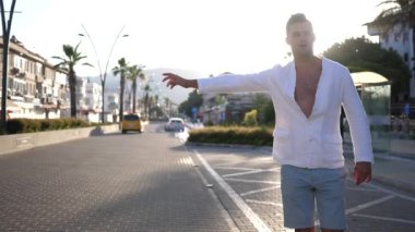 Şehir merkezinde otostop çeken genç bir adam taksiye ya da arkadan geçen bir arabaya biner.