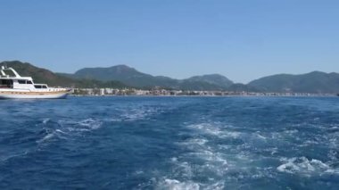 Akdeniz, mavi sularda yüzen tekne yeşil dağlarla birlikte şehrin arka planında.