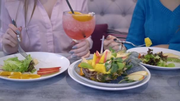 Lekker dieet, jonge vrouwen communiceren tijdens de lunch met groenten en fruit, drinkt vers sap in café — Stockvideo