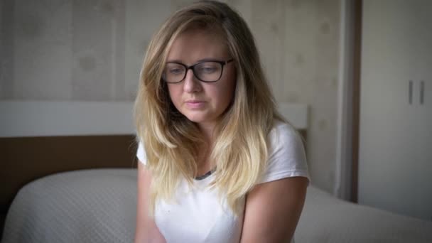 Emotional breakdown, pensive girl holds head and nervously sits on bed — Stock Video