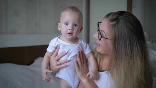 Retrato de la familia feliz, feliz madre en gafas sostiene al bebé en las manos y mira de cerca a la cámara — Vídeos de Stock