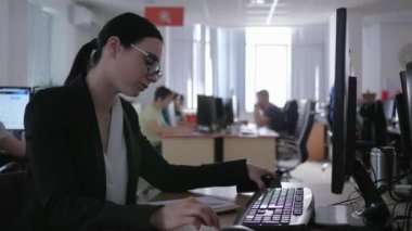 ilgisizlik, gözlüklü iş kızı bilgisayarda çalışıyor ve cep telefonu kullanıyor.