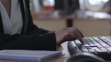 Ofis işi, gücenmiş bir kadın bilgisayar klavyesinde yazı yazıyor ve iş yerindeki bir defterde kalem girişi yapıyor.