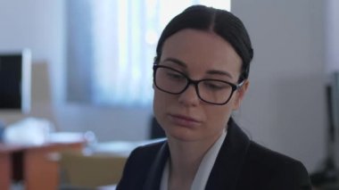 Duyarsız, mutsuz iş kadını ofiste çalışırken bir şeyler düşünür.