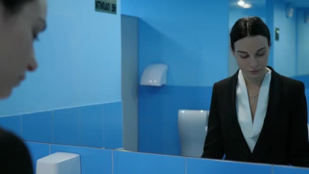 Επιχειρηματίας κυρία σε δημόσια τουαλέτα απογοητευμένοι κοιτάζει τον εαυτό της στον καθρέφτη και χρησιμοποιεί σύγχρονο smartphone — Αρχείο Βίντεο